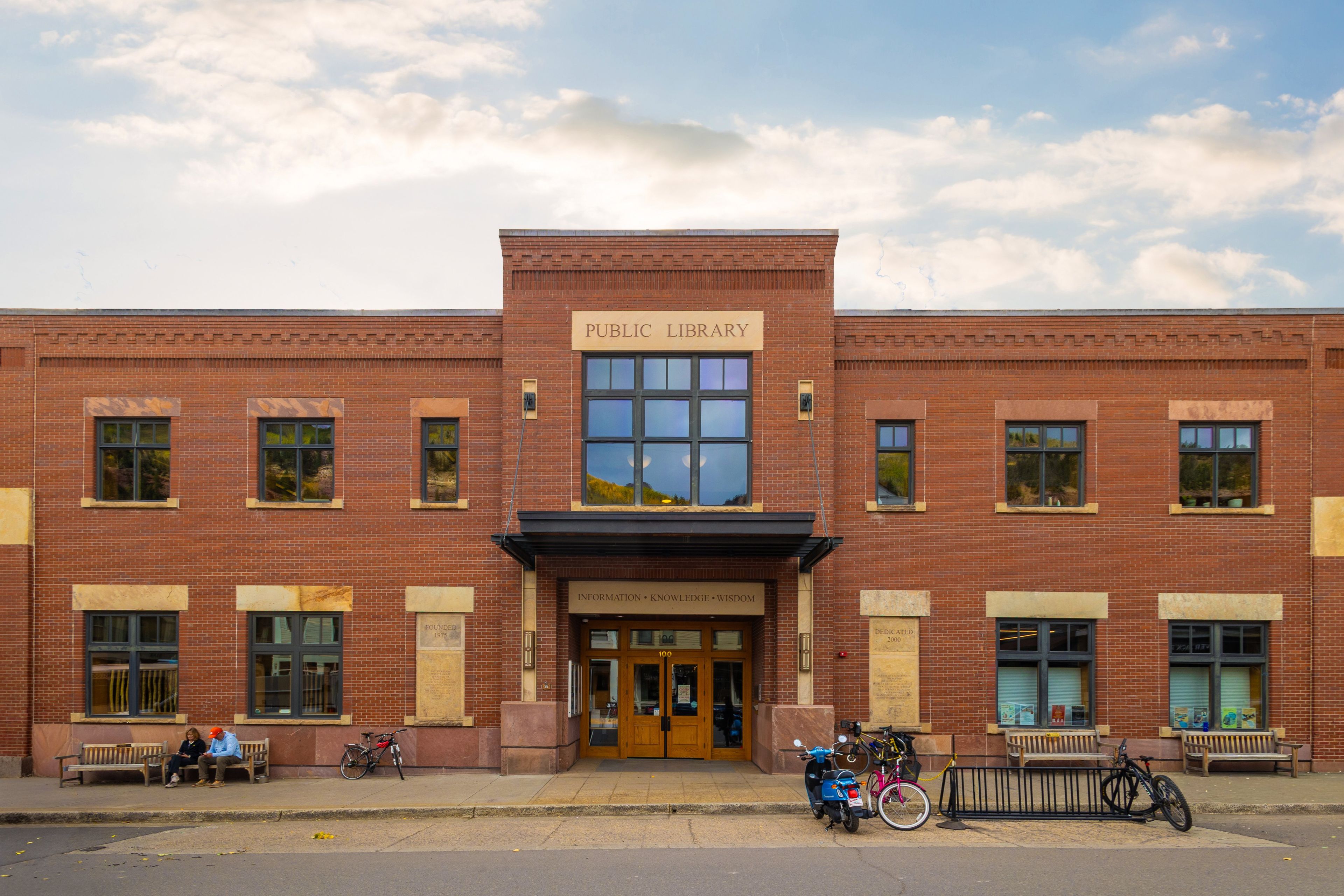 A public library with a brick facade, large windows, and a sign reading 'Public Library.'