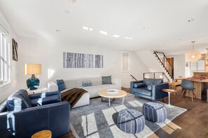 A modern living room with a sofa, two armchairs, a coffee table, and a rug. There is a staircase leading to another level. - Walk to Ski! Luxury Telluride Townhome | Walk to Gondola, Main Street & River Trail |  | Sleeps 8 (Telluride)