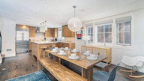 Eine moderne Küche mit Holzschnitzereien, einem Edelstahlkühlschrank und einem Essbereich mit einem Holztisch, gedeckt für vier Personen.