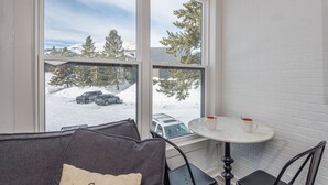 A cozy room with a view of a snowy parking area and trees.
