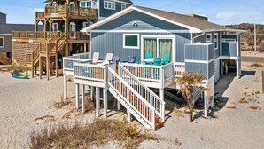 Ein Strandhaus mit Holzterrasse, mehreren Ebenen und Außenmöbeln.