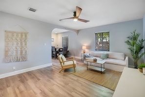 Relax in this inviting living space with a high ceiling, wooden floor, and plush sofa.
