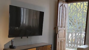 Un soggiorno con televisione a schermo piatto montata a parete, un mobile porta TV in legno, un tappeto decorato e un balcone con vista.