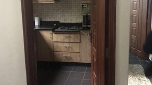 Una cucina stretta con mobili in legno, paraschizzi piastrellato e un piano cottura.