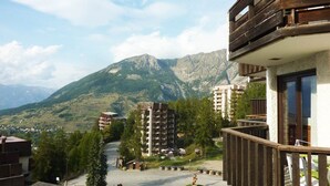 Vista de un estacionamiento con edificios y montañas al fondo.