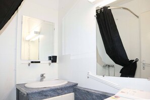 A bathroom with a white sink, a mirror, a black shower curtain, and a white bathtub. - 32 LES Gradins lES Orres 1650 (LES ORRES 1650)