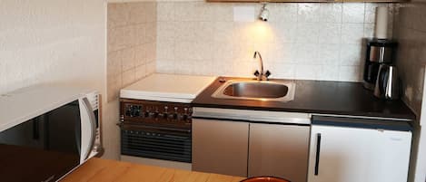 Een koelkast, een oven, kookgerei, borden en bestek