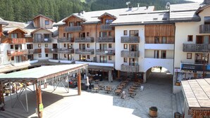 Un edificio de estilo chalet con balcones de madera y una terraza con mobiliario exterior.