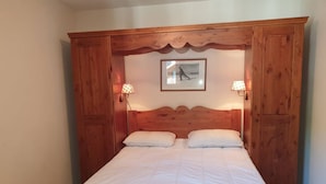 Un dormitorio con cabecera de madera, dos lámparas de noche y un cuadro en la pared.