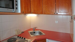 Una cocina compacta con armarios de madera, un microondas, un fregadero y una estufa.