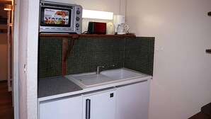 A compact kitchenette with a microwave, coffee maker, and sink.