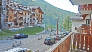 A mountain lodge with multiple wooden balconies and a parking area in front. - 2222 LES Silenes 1800 (LES ORRES 1800)