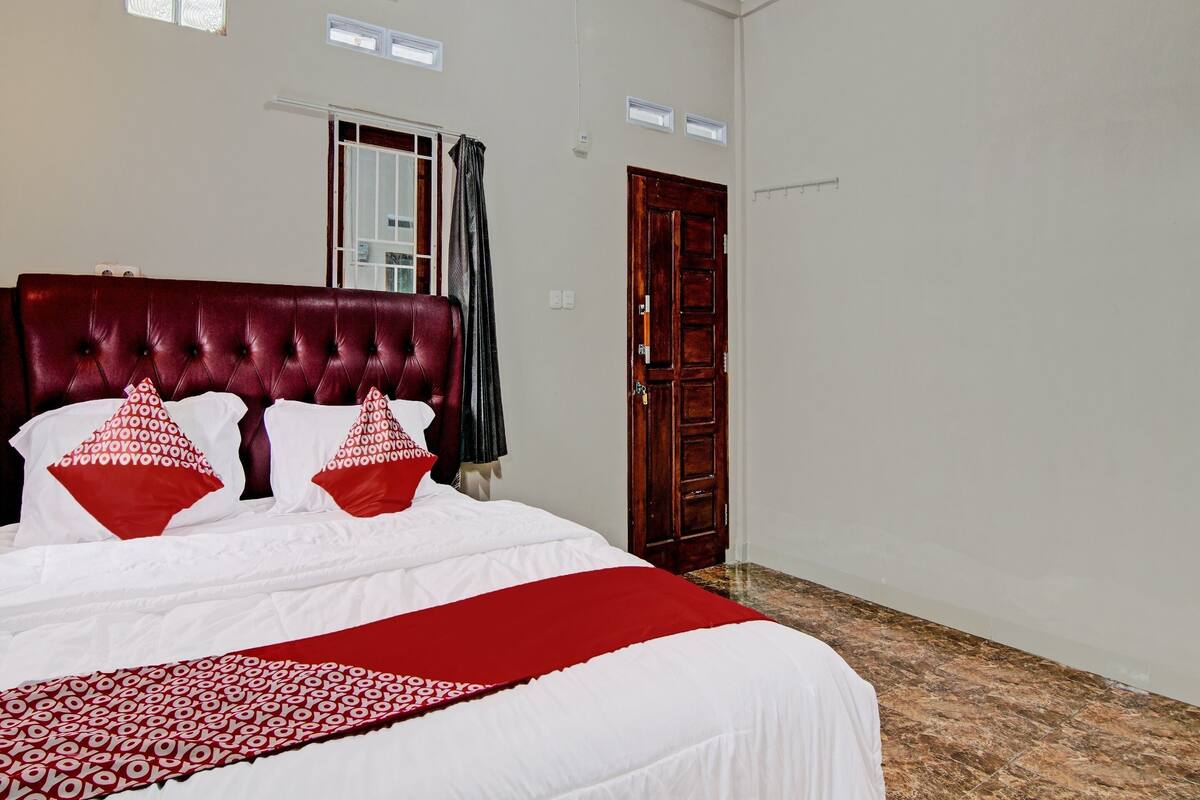 Un dormitorio con una cama grande, una puerta de madera y una ventana con cortinas.
