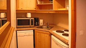 A compact kitchen with a microwave, coffee maker, sink, dishwasher, and stove.