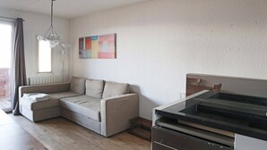 A modern living room with a sectional sofa, a dining table, and a kitchen area with a refrigerator and oven. - 130 LE Sunny Snow 1650 (LES ORRES 1650)
