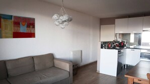 A modern living room with a sofa, a dining table, and a kitchen area with cabinets and appliances. - 130 LE Sunny Snow 1650 (LES ORRES 1650)