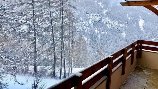 A balcony with a wooden railing overlooking a snow-covered forest and mountains. - N°101 Balcon des Airelles (LES ORRES 1800)