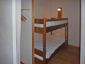 Cozy retreat with a wooden bunk bed, shelf, and wall-mounted light.