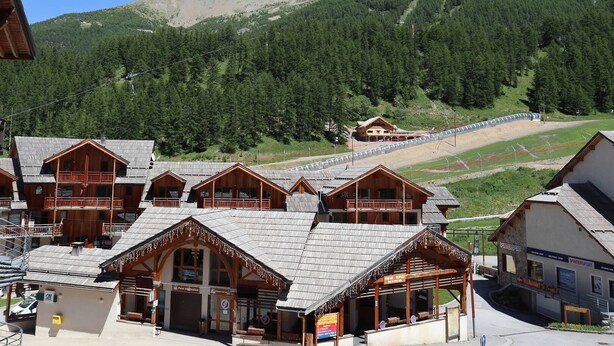 Un chalet de montagne composé de plusieurs bâtiments en bois, avec un accès aux pistes de ski et une vue sur la montagne.