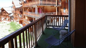 Un chalet en bois doté d’un balcon, d’un espace extérieur aménagé et offrant une vue sur d’autres chalets.