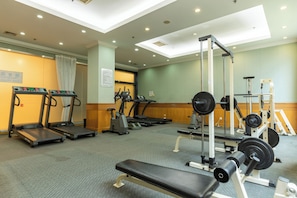A gym with treadmills, elliptical machines, a bench, and weightlifting equipment.