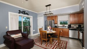 Une cuisine moderne avec des meubles en bois, un réfrigérateur en acier inoxydable et un coin repas agrémenté d’un tapis à motifs rouges.