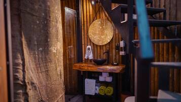 A rustic bathroom with a wooden vanity, a round mirror, and a toilet.