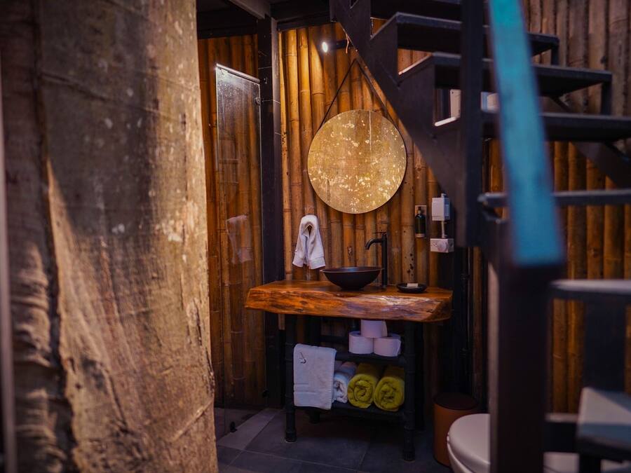 A rustic bathroom with a wooden vanity, a round mirror, and a toilet.