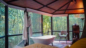 A room with a large window, a bathtub, a chair, and a bed. - Amanatu Ecolodge & Spa  (Quimbaya)