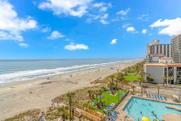 A beach resort with a swimming pool, beach, and ocean view.