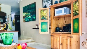 Een woonkamer met een houten kast, een glazen salontafel met bloemen en een schilderij van een vijver.