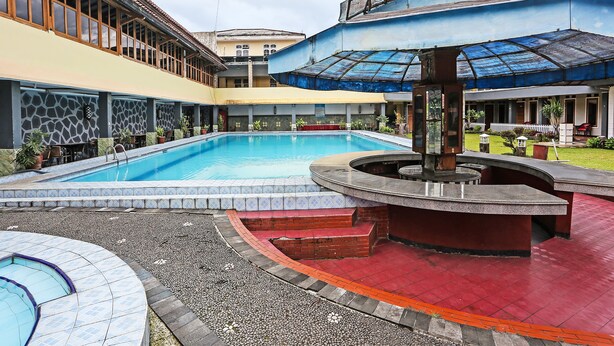 A swimming pool with a surrounding deck, a covered seating area, and a small fountain. - OYO 92088 171 Inn (Bogor)