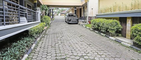 Un sendero pavimentado con baldosas hexagonales, bordeado de vegetación y edificios con balcones.