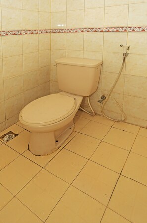Un inodoro en un baño con paredes y suelo de baldosas.
