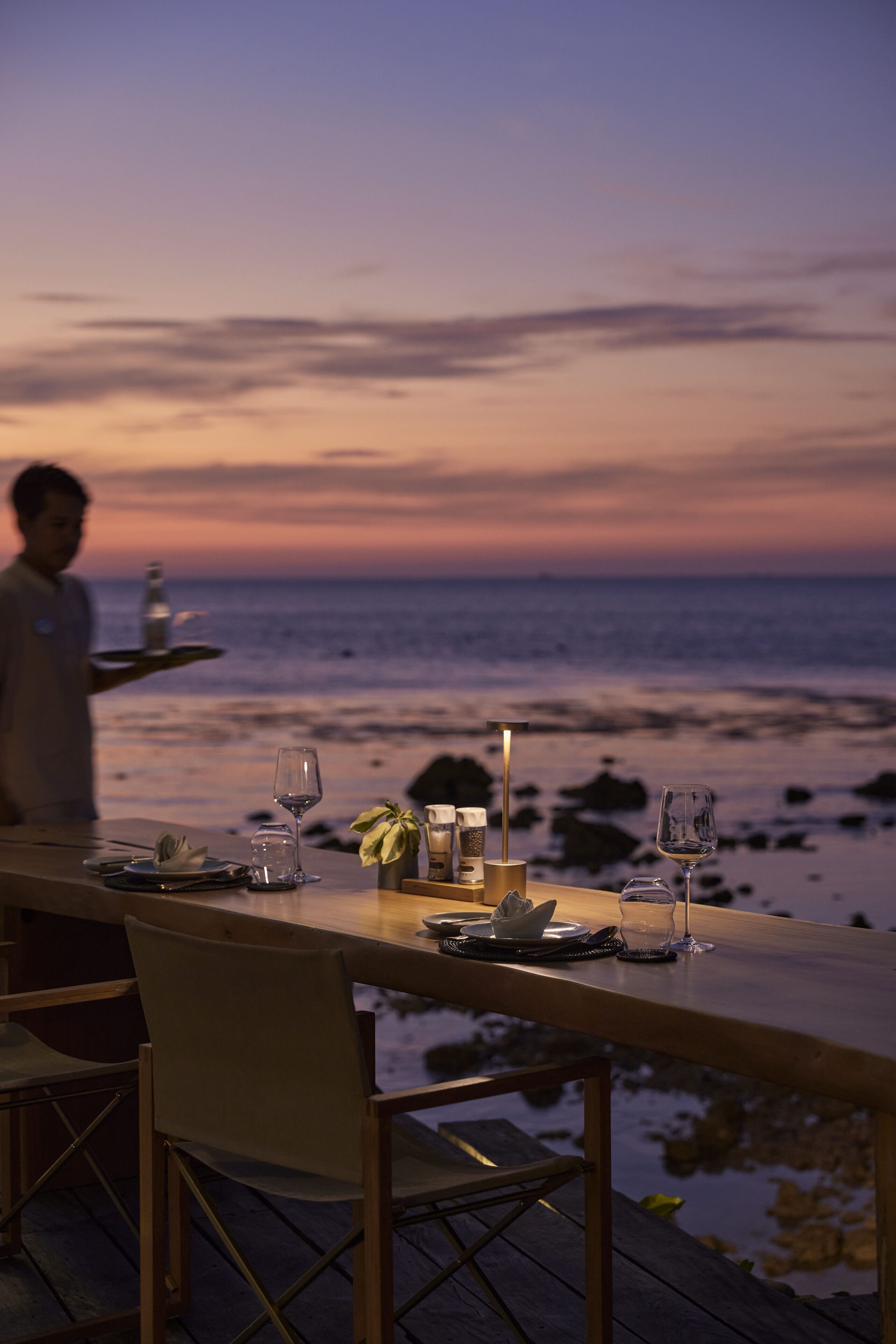 Mesa para dos con vista al océano al atardecer.