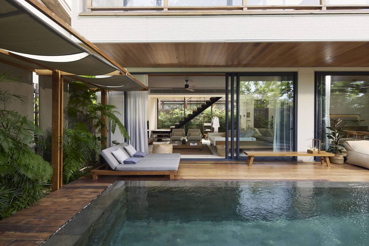 A modern house with a swimming pool, wooden flooring, and a staircase leading to a balcony.