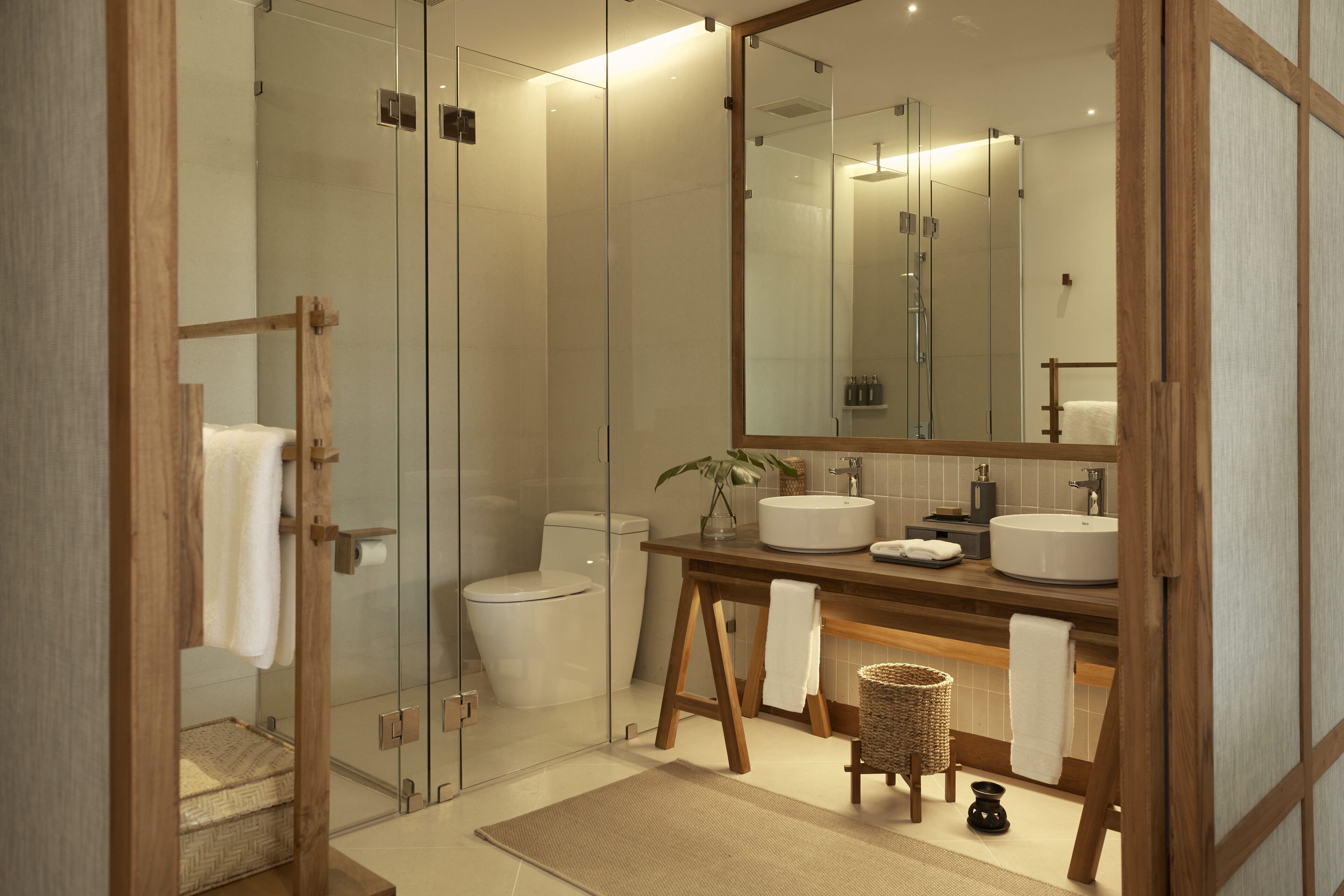 Un baño moderno con cabina de ducha de vidrio, tocador de madera y un espejo grande.