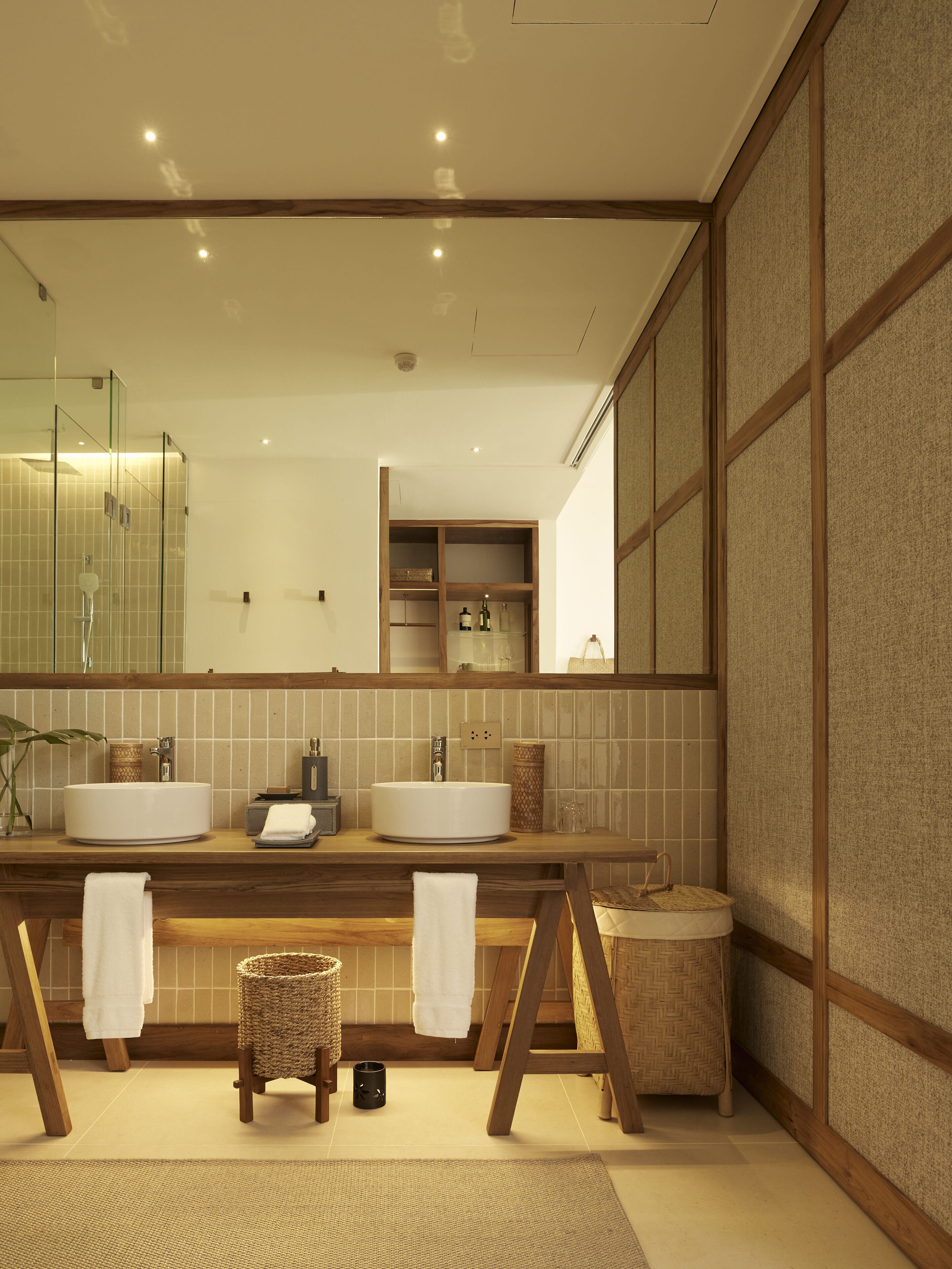 A modern bathroom with two sinks, a large mirror, and a wooden vanity.