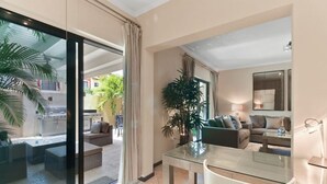Ein modernes Wohnzimmer mit einem Glastisch, zwei Sofas und einer großen Topfpflanze.