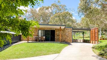 A modern house with a covered patio, stone exterior, and a well-maintained lawn.