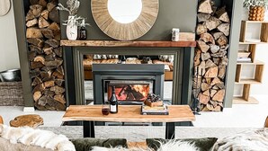 Una sala de estar acogedora con chimenea, un espejo redondo y un sofá con un plaid suave.