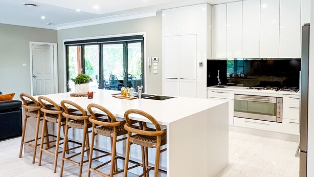 Una cocina moderna con una isla central, taburetes de bar y electrodomésticos integrados.