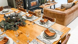 Un comedor con una mesa de madera dispuesta para una comida, una chimenea y un árbol de Navidad.