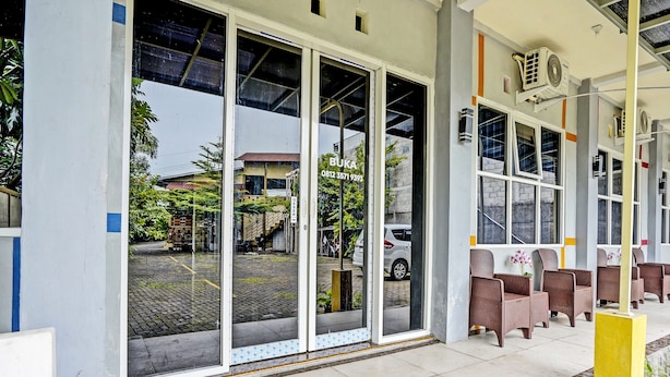 A hotel entrance with a covered outdoor seating area, large windows, and air conditioning units. - OYO 92117 Fa Homestay Syariah (Babat)