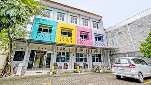 A multi-story building with colorful facades and a parking area. - OYO 92117 Fa Homestay Syariah (Babat)