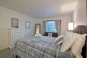 Ein Schlafzimmer mit Bett, Kommode, Spiegel und einem Fenster mit Vorhängen.