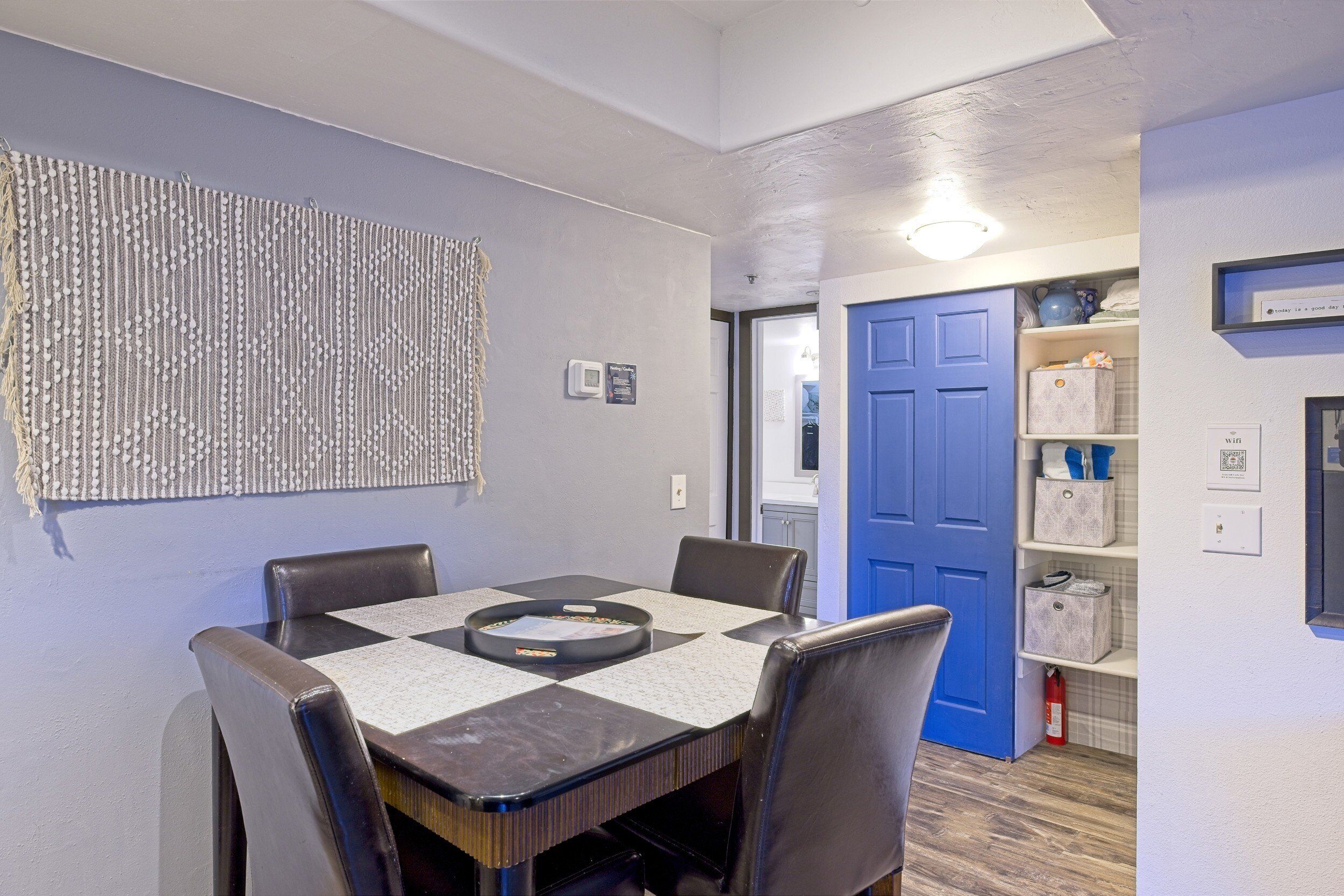 A dining area with a checkered tablecloth, black chairs, and a wall-mounted decorative piece.