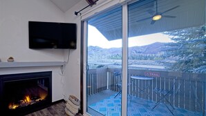 A balcony with a glass door, a fireplace, and a mounted TV. - Park City Mountain View Condo | Amazing Ski Location! (Park City)