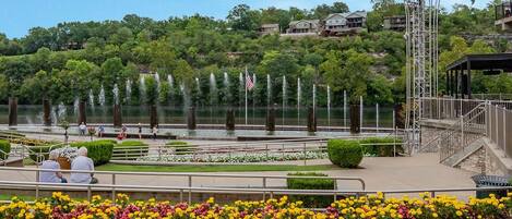 A waterfront park with a fountain, flower beds, and a gazebo.