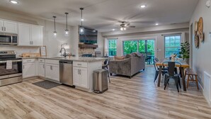 Una cocina moderna con armarios blancos, una isla central y un comedor con mesa y sillas.